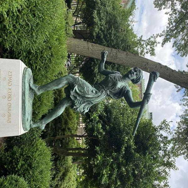 Head on shot of Greek Games statue and base with greenery in the background